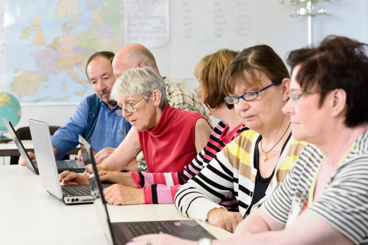 A group of people sitting at a table with laptops.