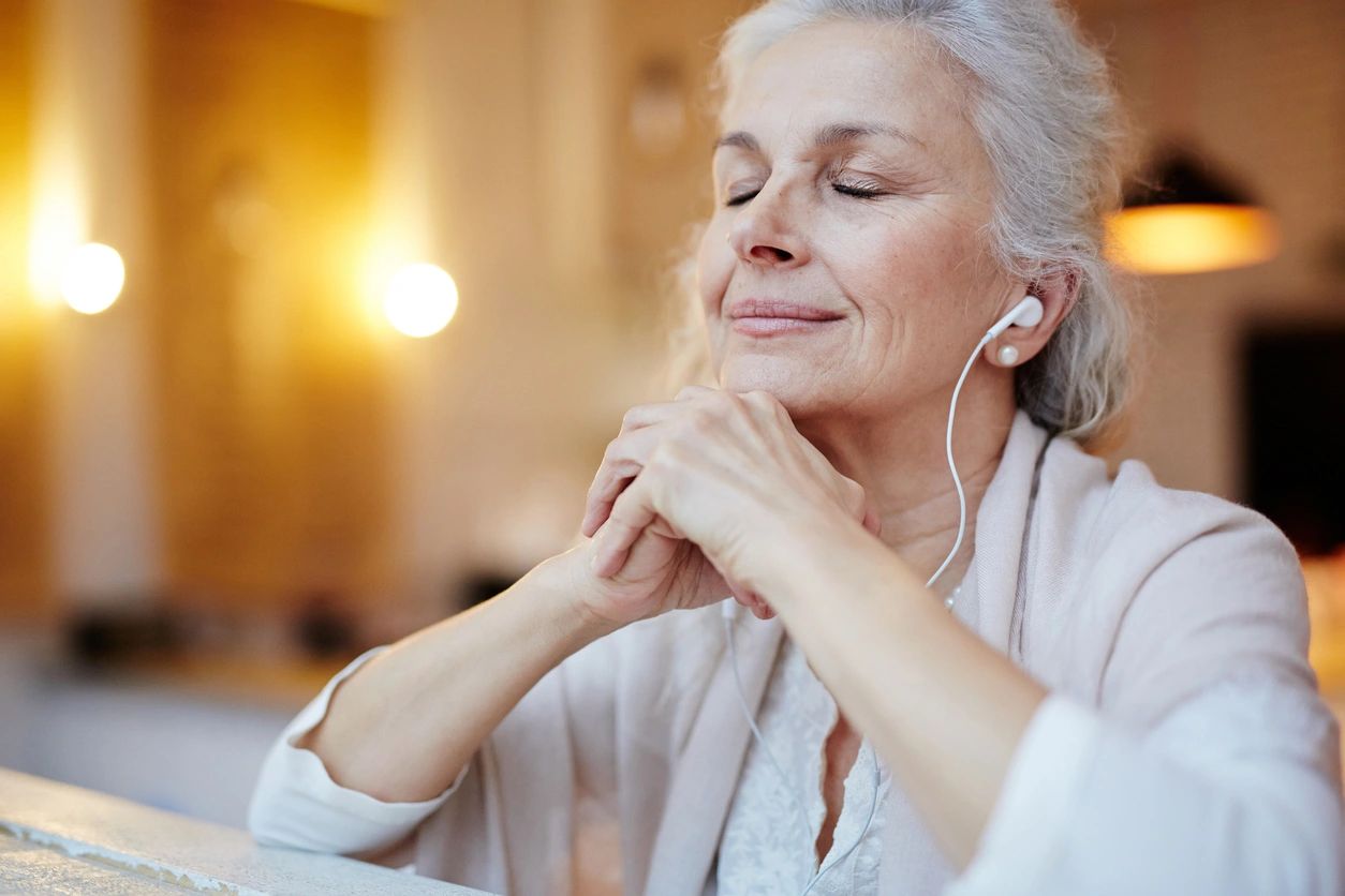A woman with her eyes closed listening to music.