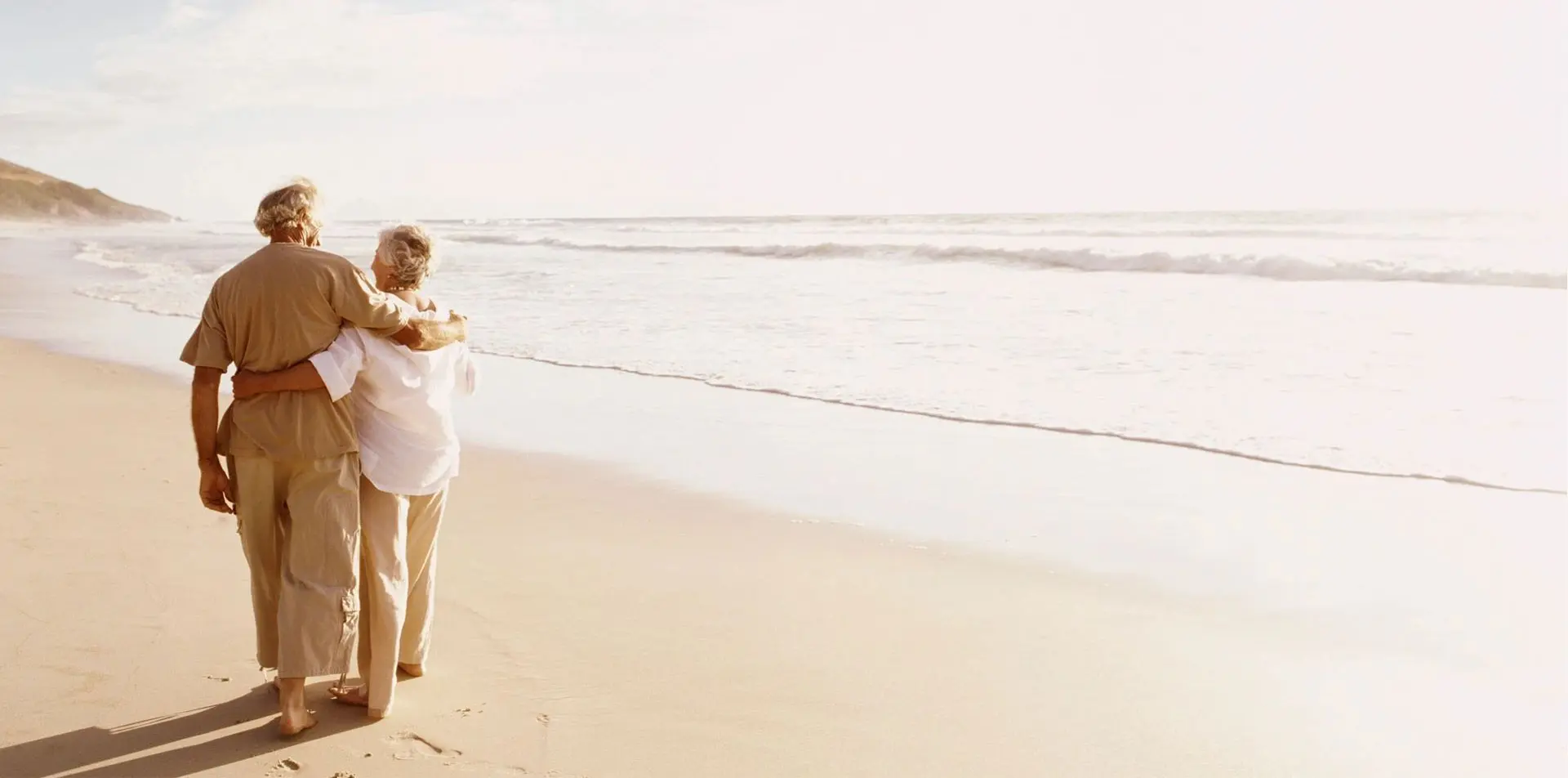 A woman walking on the beach with her dog.